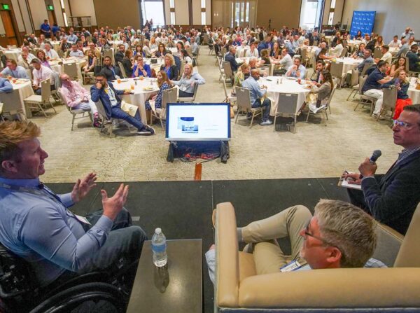 Luke Spink, Doug Anderson and Dan Ryan in a panel discussion in a large conference room.