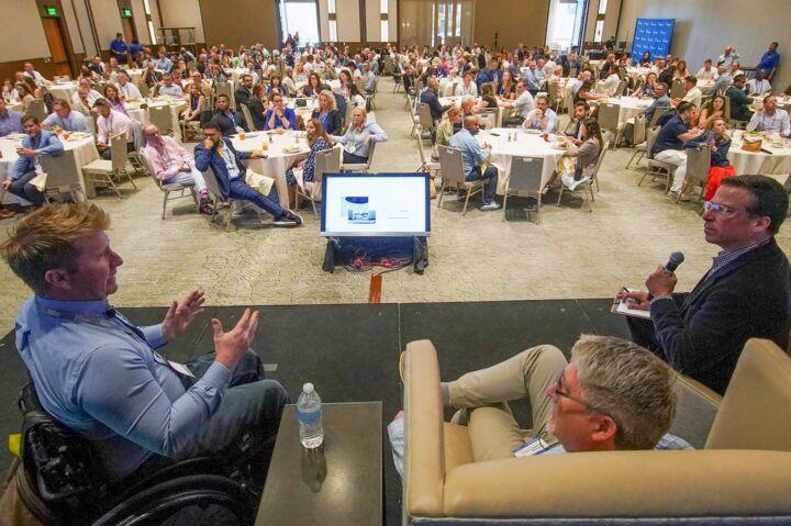 Luke Spink, Doug Anderson and Dan Ryan in a panel discussion in a large conference room.