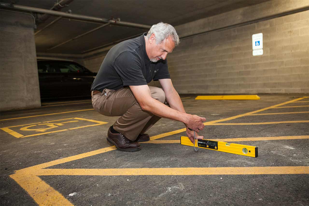 Richard Seneczko measuring the slope of an accessible parking space.