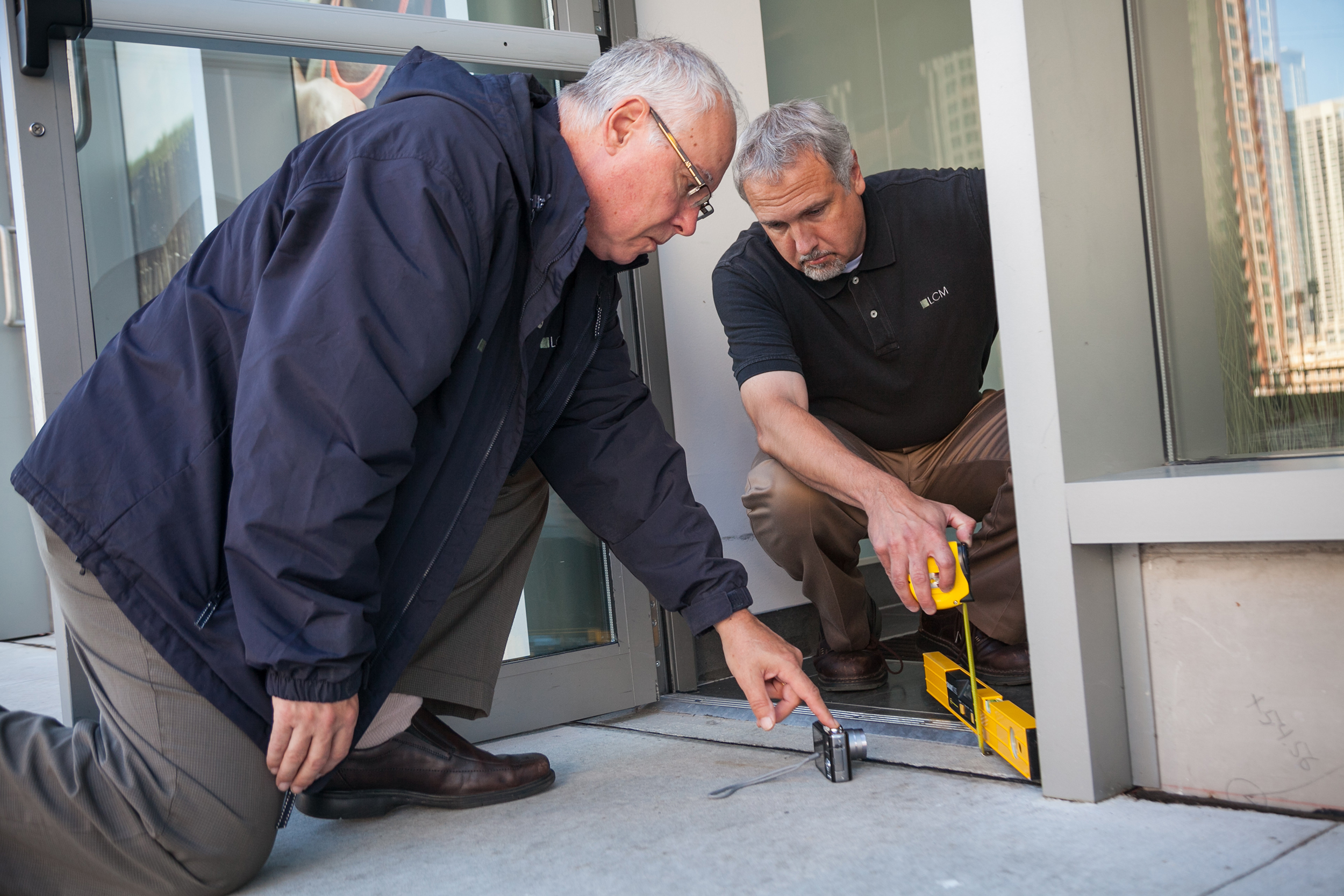 Richard Seneczko and Joe Kucera photographing the height of the threshold of a door.