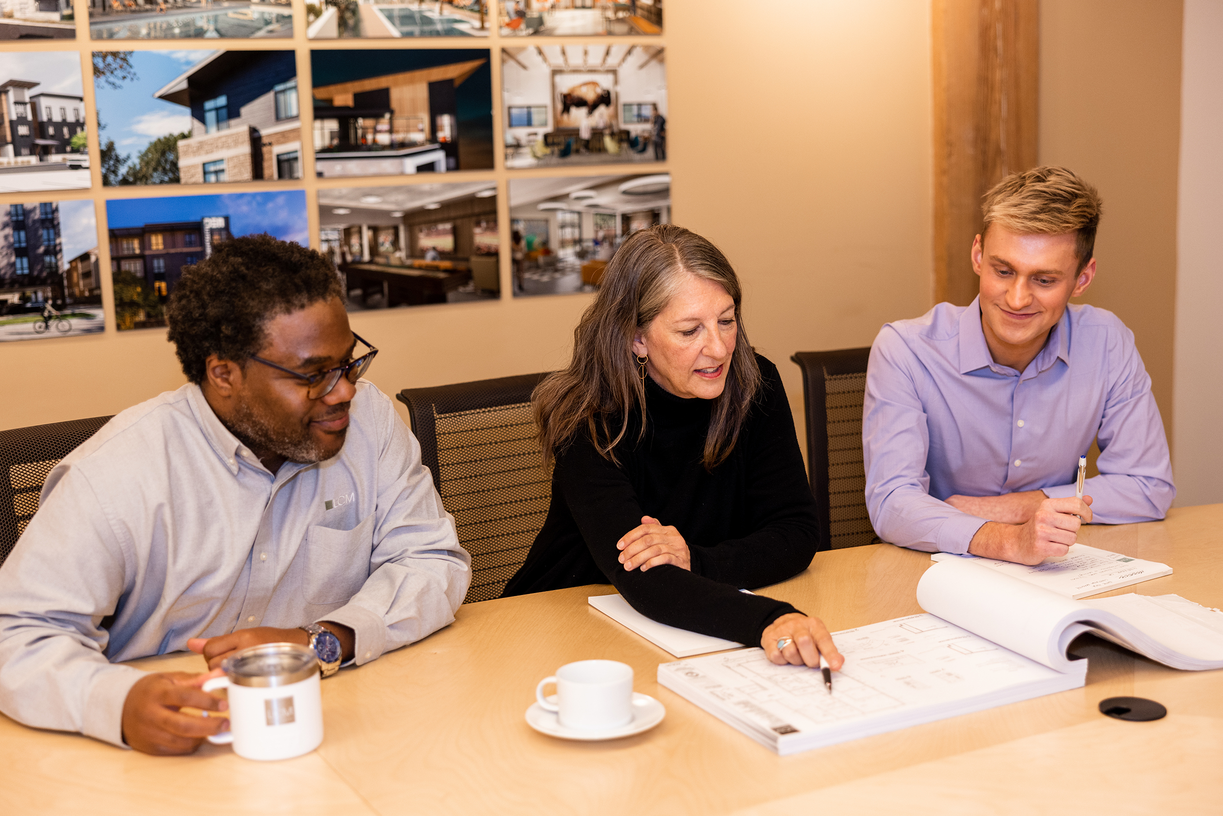 Michael Arnold, Elizabeth Zaverdas, and Trenton Werner looking at architectural drawings.