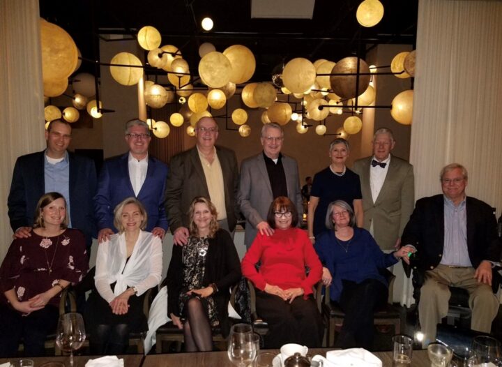 The partners with their wives at a restaurant.