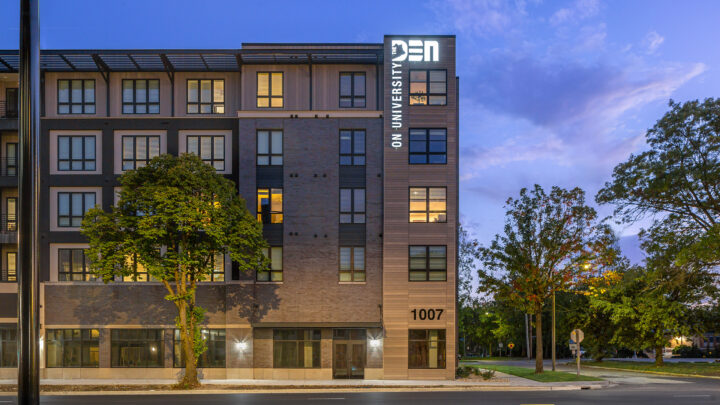 Den on University facade at dusk.