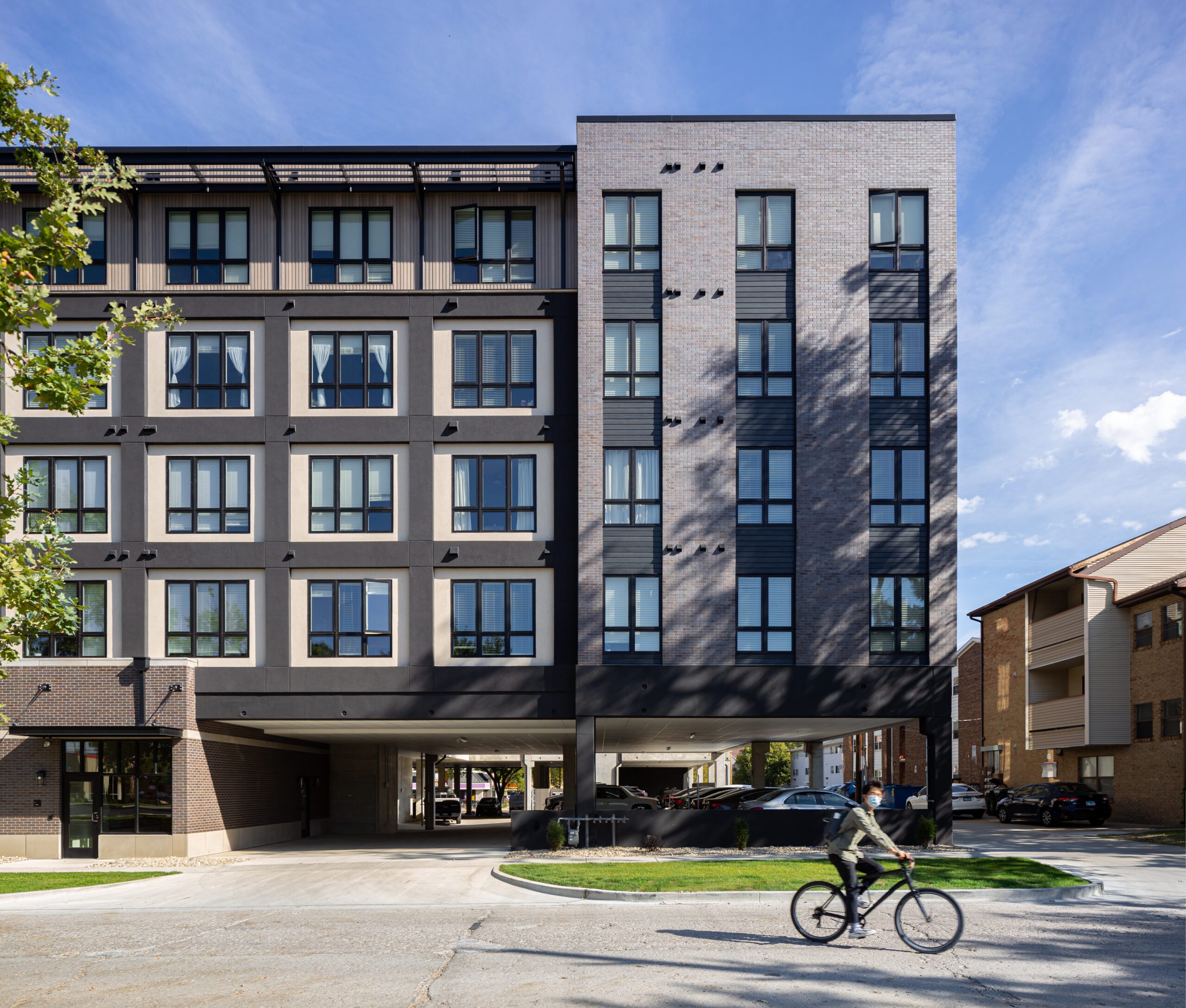 West side elevation view of the Den on University with a bike passing on the street.