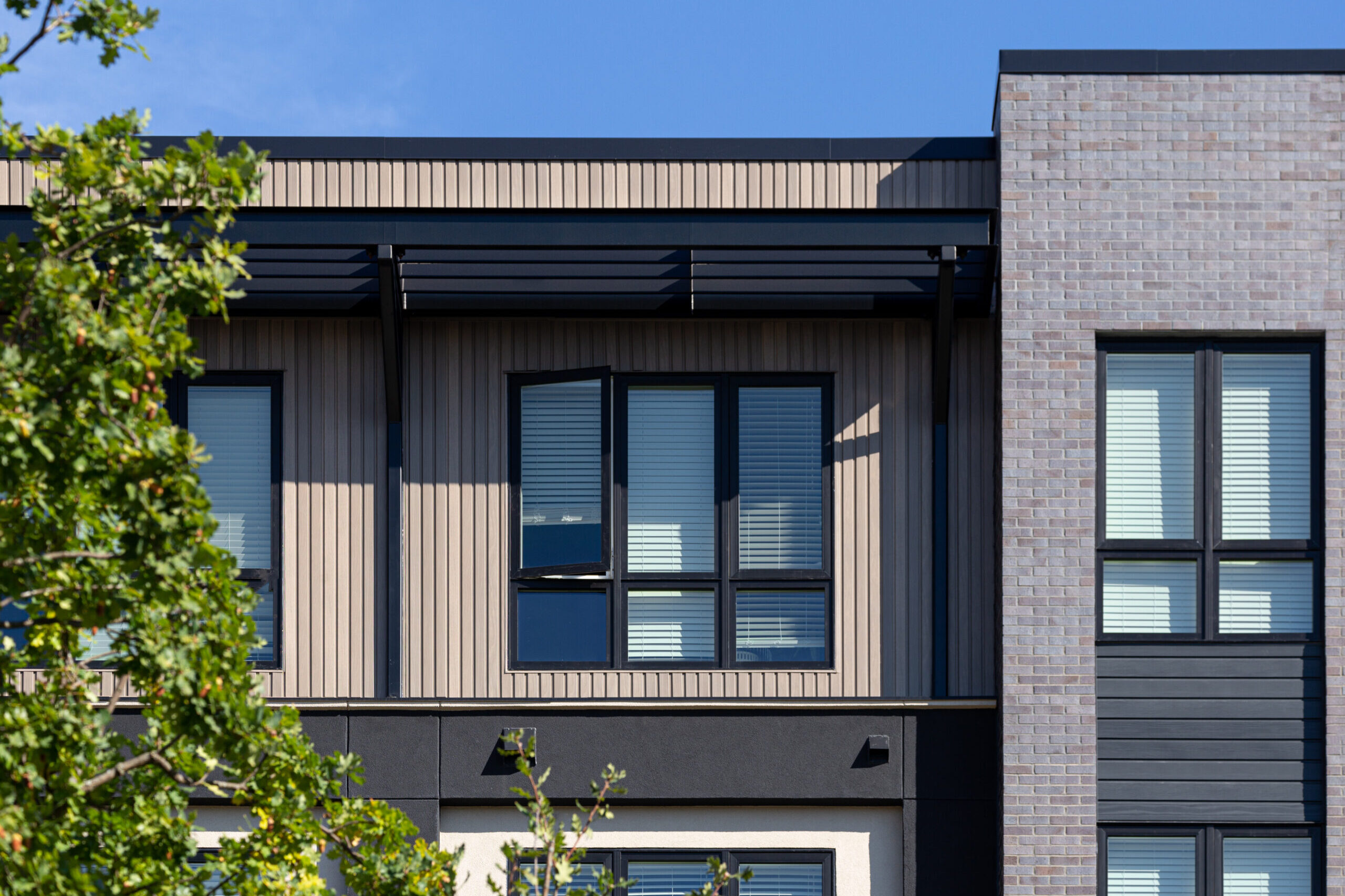 Close up view of building facade showing window, screen, and brick details.