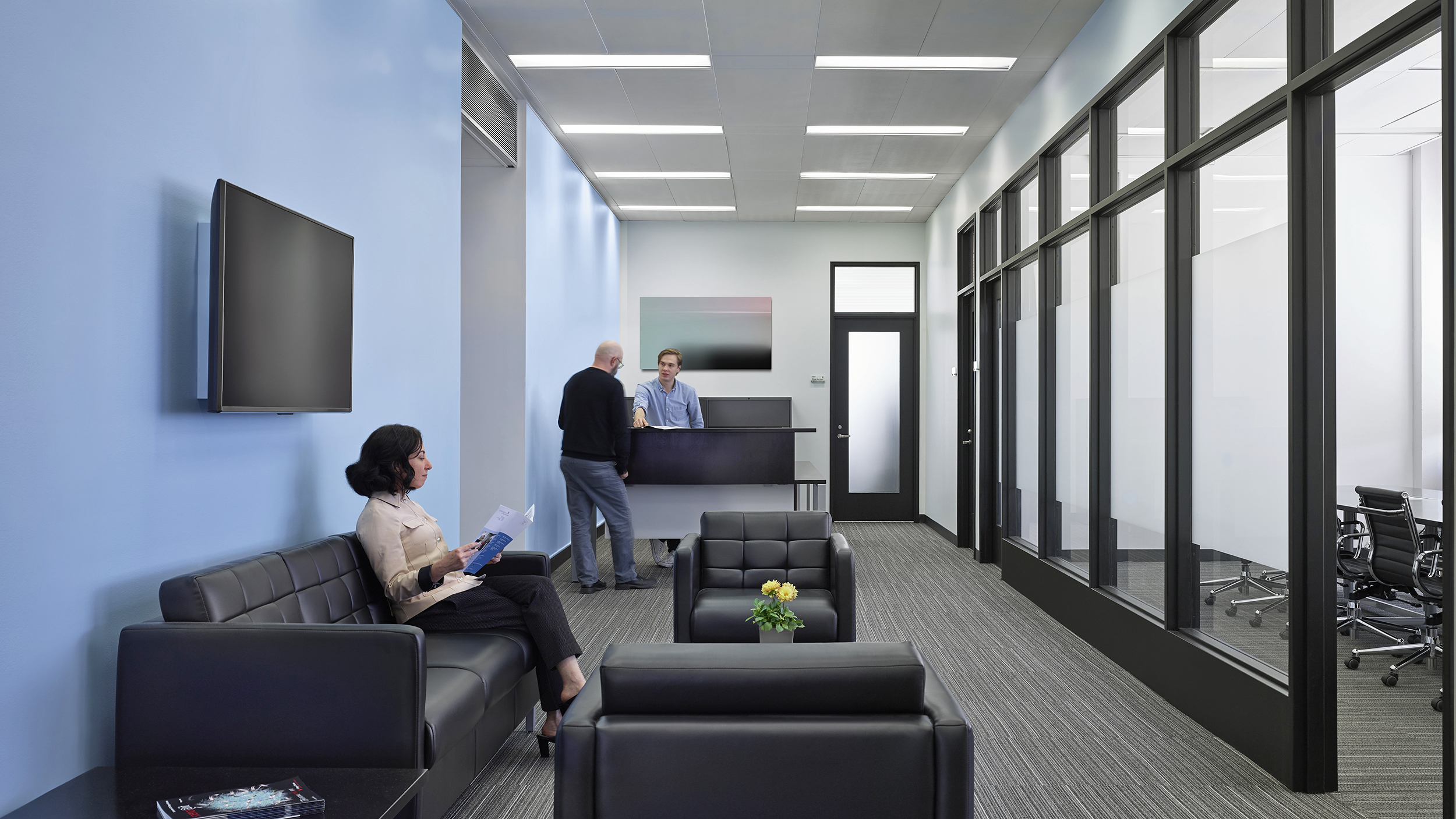 Reception area in the Dean’s suite with blue walls and glass partitions separating private offices.