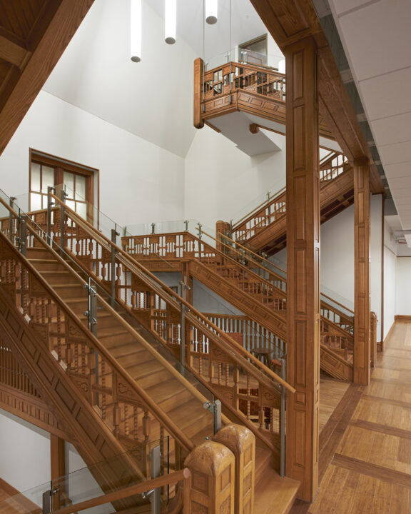 Perspective view of two ornately carved wooden stairways in the renovated Natural History Building.