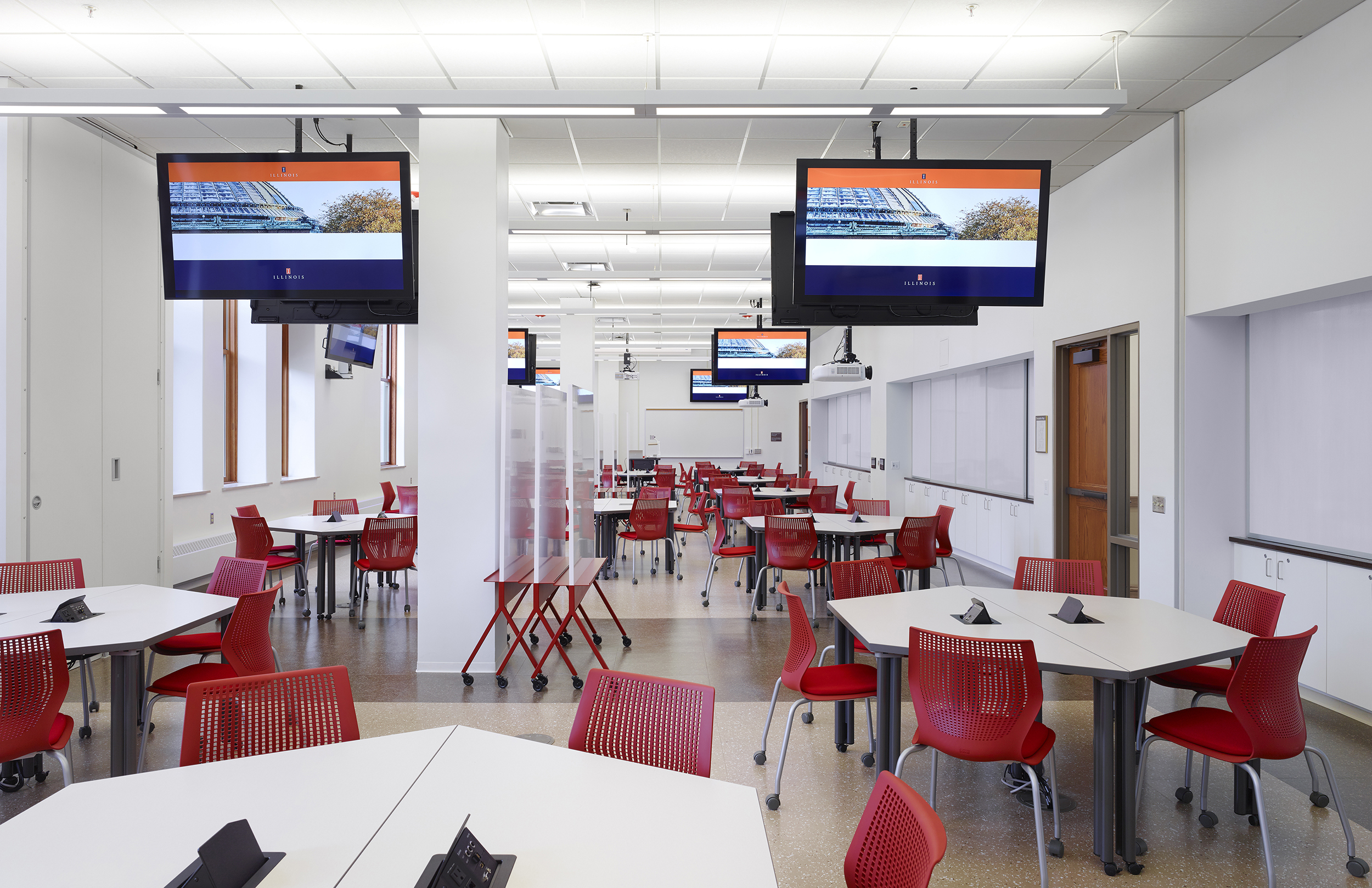 Peer-to-peer classroom with modular furniture on wheels and suspended monitors.