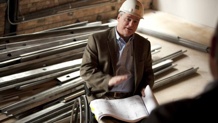 LCM co-founder Jack Catlin on work site in wheelchair wearing and hard hat.