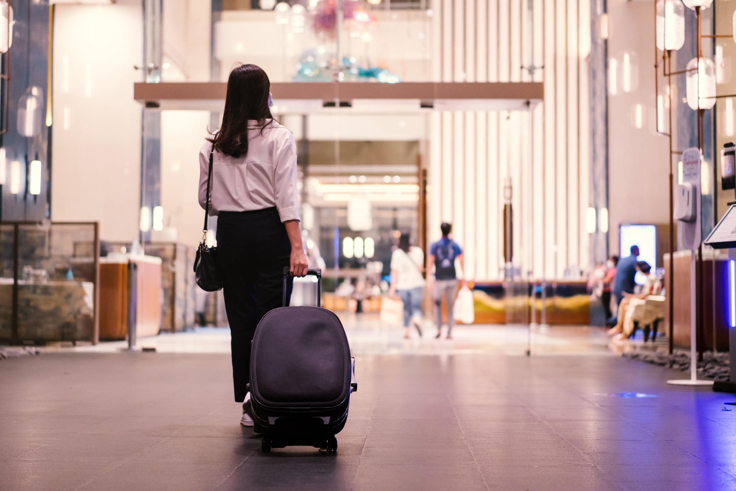 Woman with her suitcase heading into a hotel lobby.