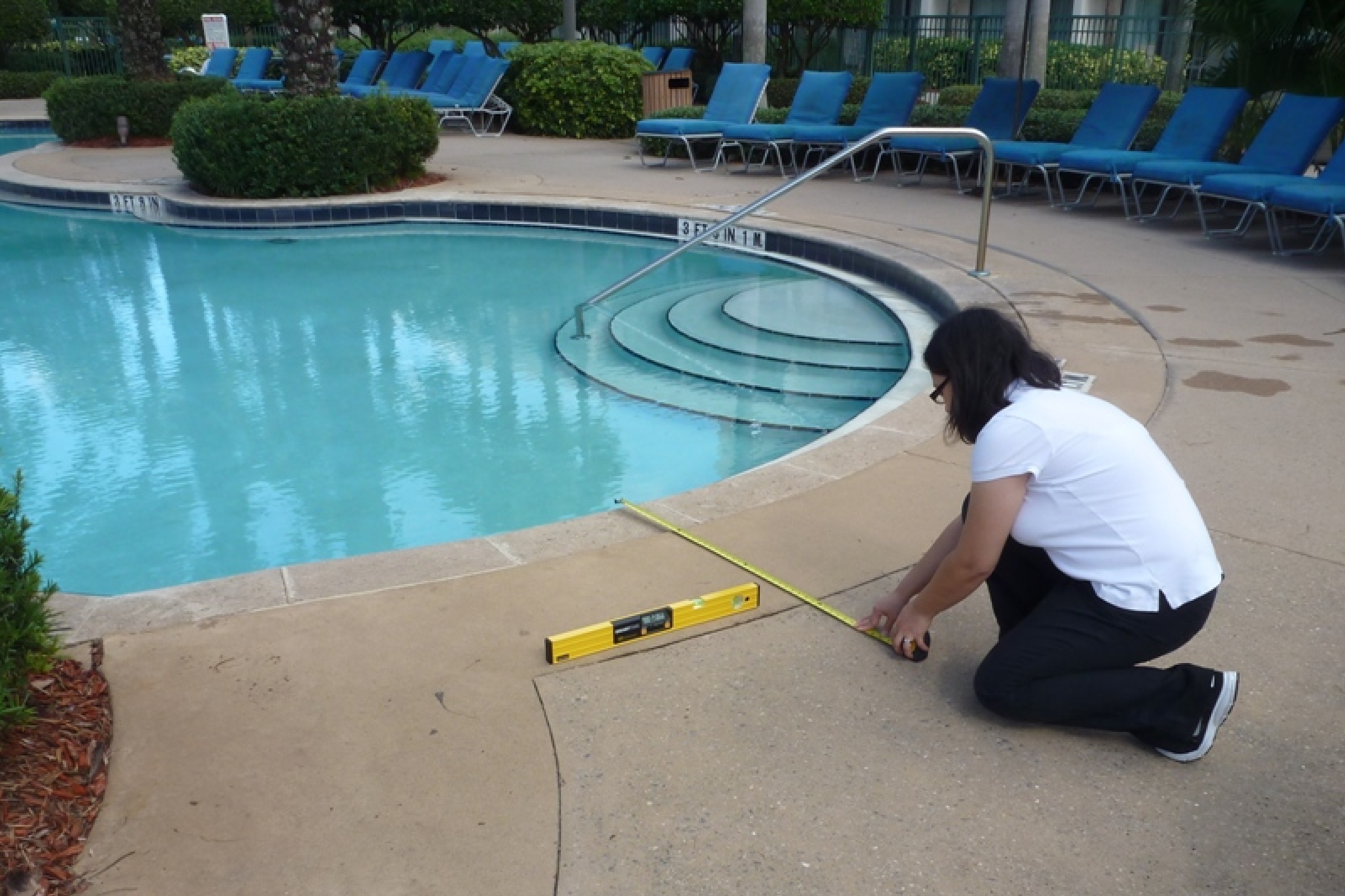 Michelle Winnecke measuring the distance between the pool and the walkway.